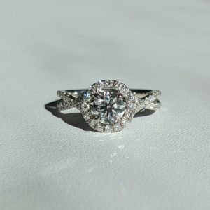 Round diamond engagement ring with a halo connected to crossing split diamond band.