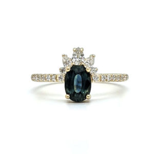 Oval teal sapphire ring with a crown of 5 pear and round diamonds and a pave band, set in yellow gold.